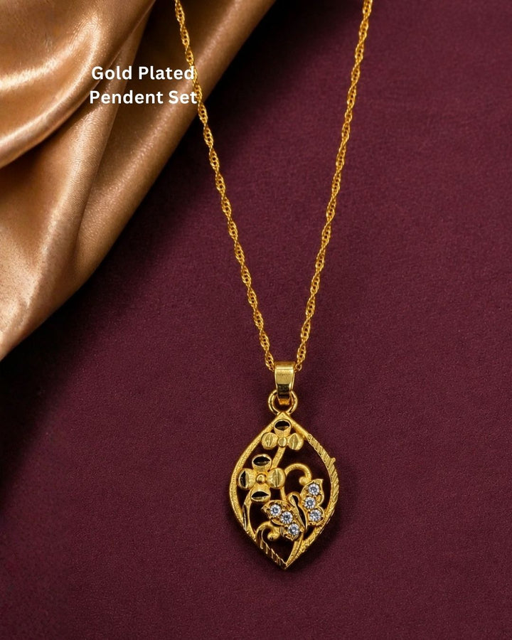 Beautiful gold plated leaf pendant featuring intricate floral patterns and CZ-style stones on a rich maroon background.