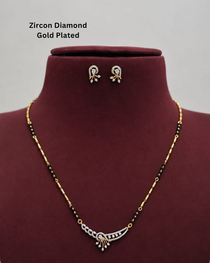 Gold-plated zircon diamond necklace and matching stud earrings displayed on a dark red jewelry bust. The necklace features a gold-plated curved pendant with clear stones and black beads along the chain.