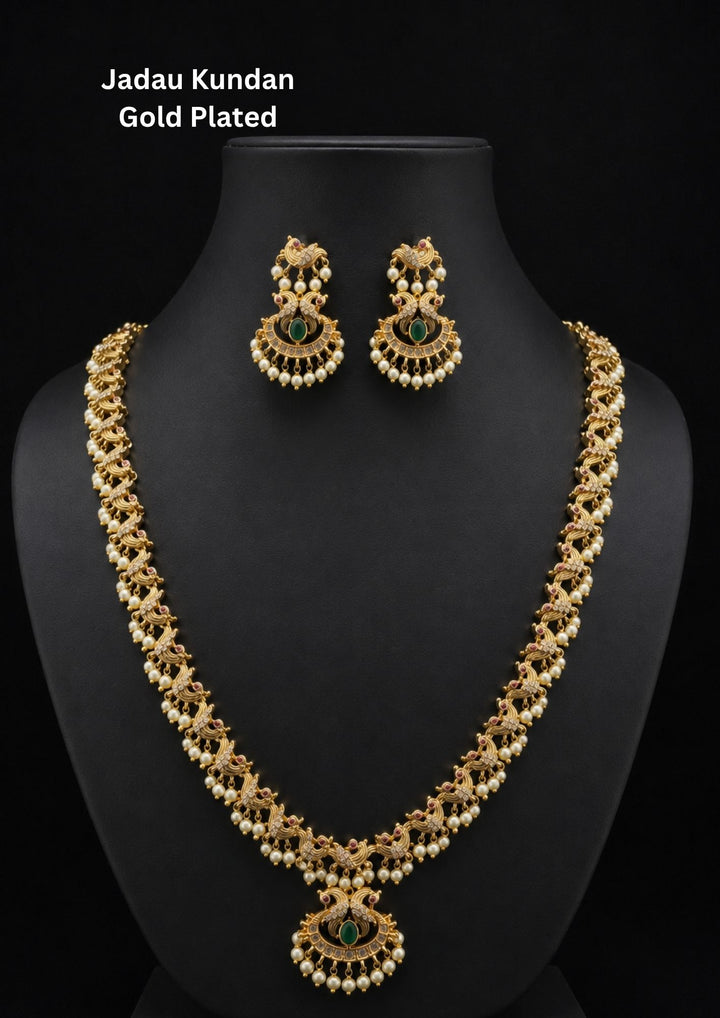 Elegant gold plated peacock temple necklace set featuring intricate peacock motifs, emerald green center stones, pearl drop detailing, and a beautifully crafted matching pendant with coordinated earrings. Perfect for weddings and festive occasions.