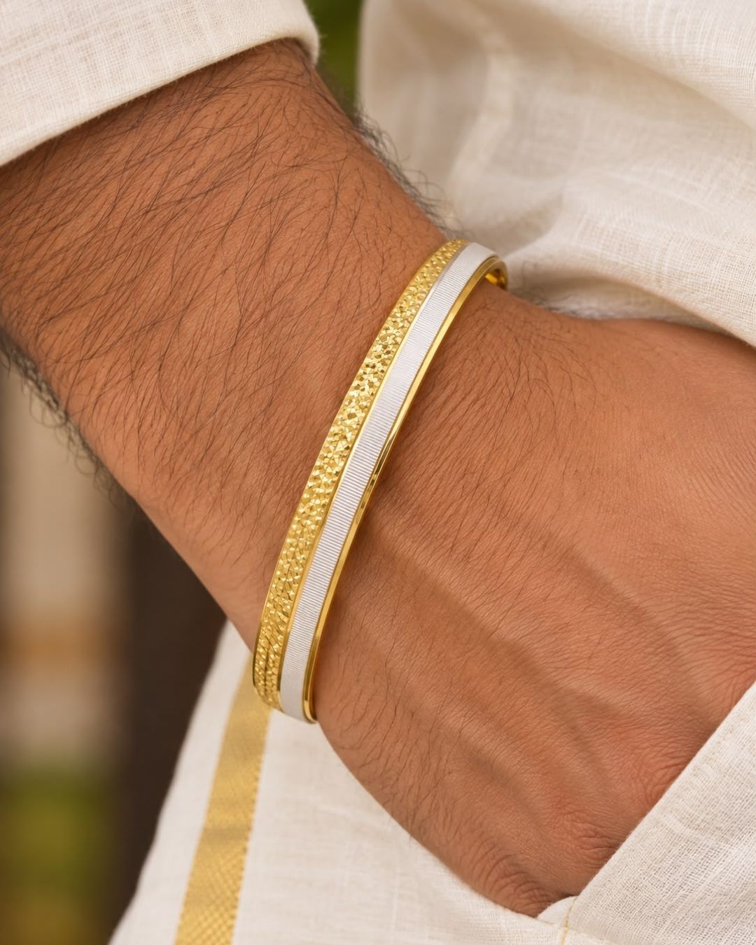 Elegant gold plated men’s kada featuring a sleek dual-tone design, intricate textured detailing along the outer band, and a contrasting silver-tone center strip, perfect for daily wear, festive occasions, parties, and modern looks.