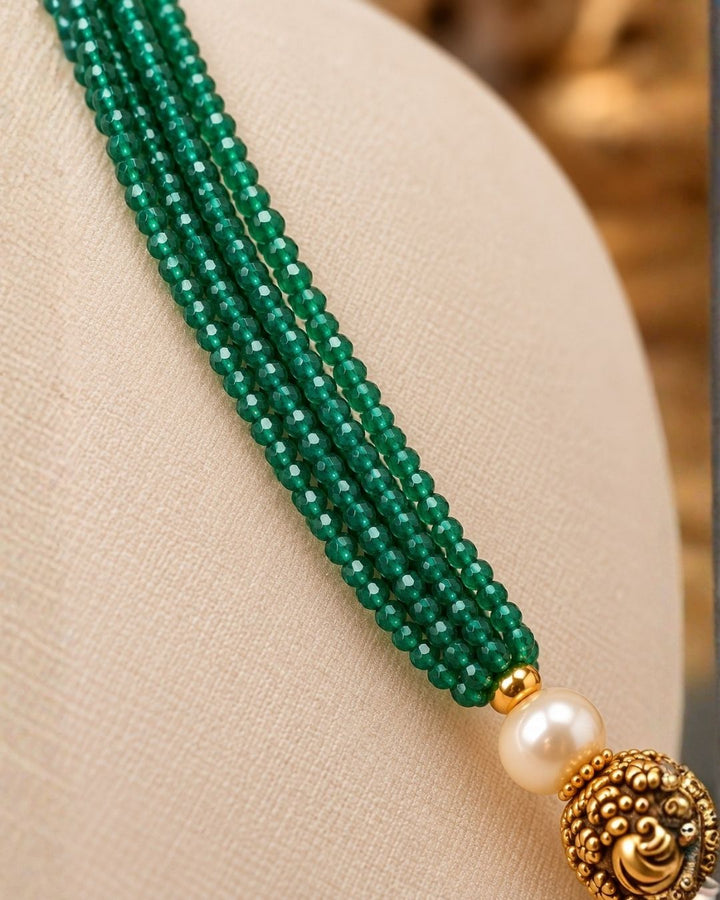 Traditional gold plated emerald beads necklace featuring multiple green bead strands, pearl accents, detailed gold motifs, and an elegant center pendant, perfect for festive and traditional wear.