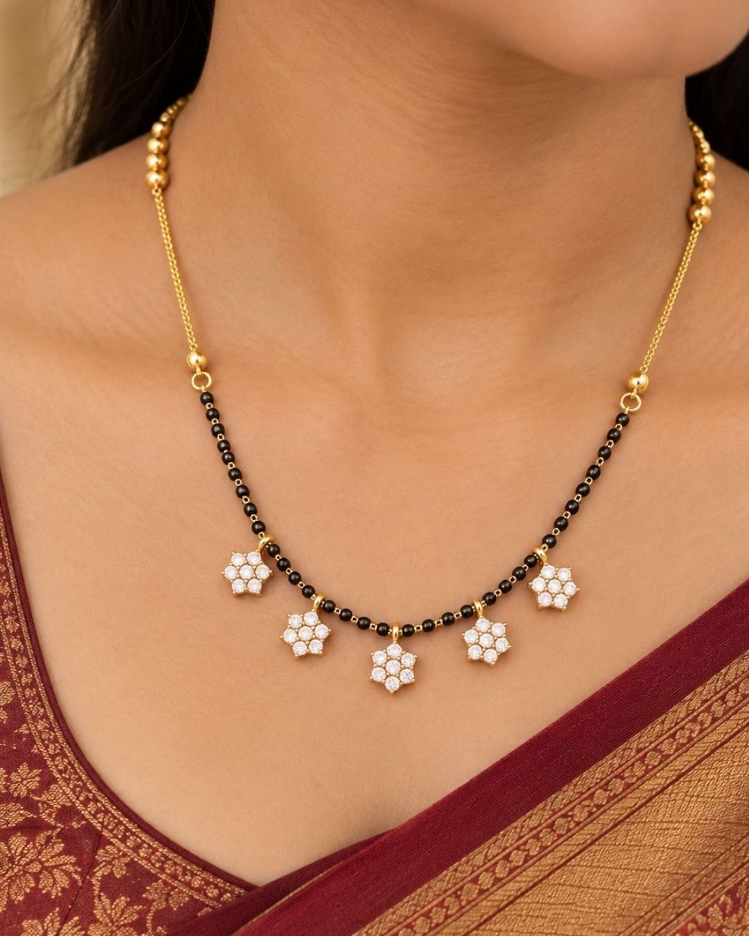 Premium gold plated mangalsutra featuring a delicate black bead chain and five floral CZ pendant motifs, suitable for everyday wear, festive occasions, parties, weddings, and gifting.