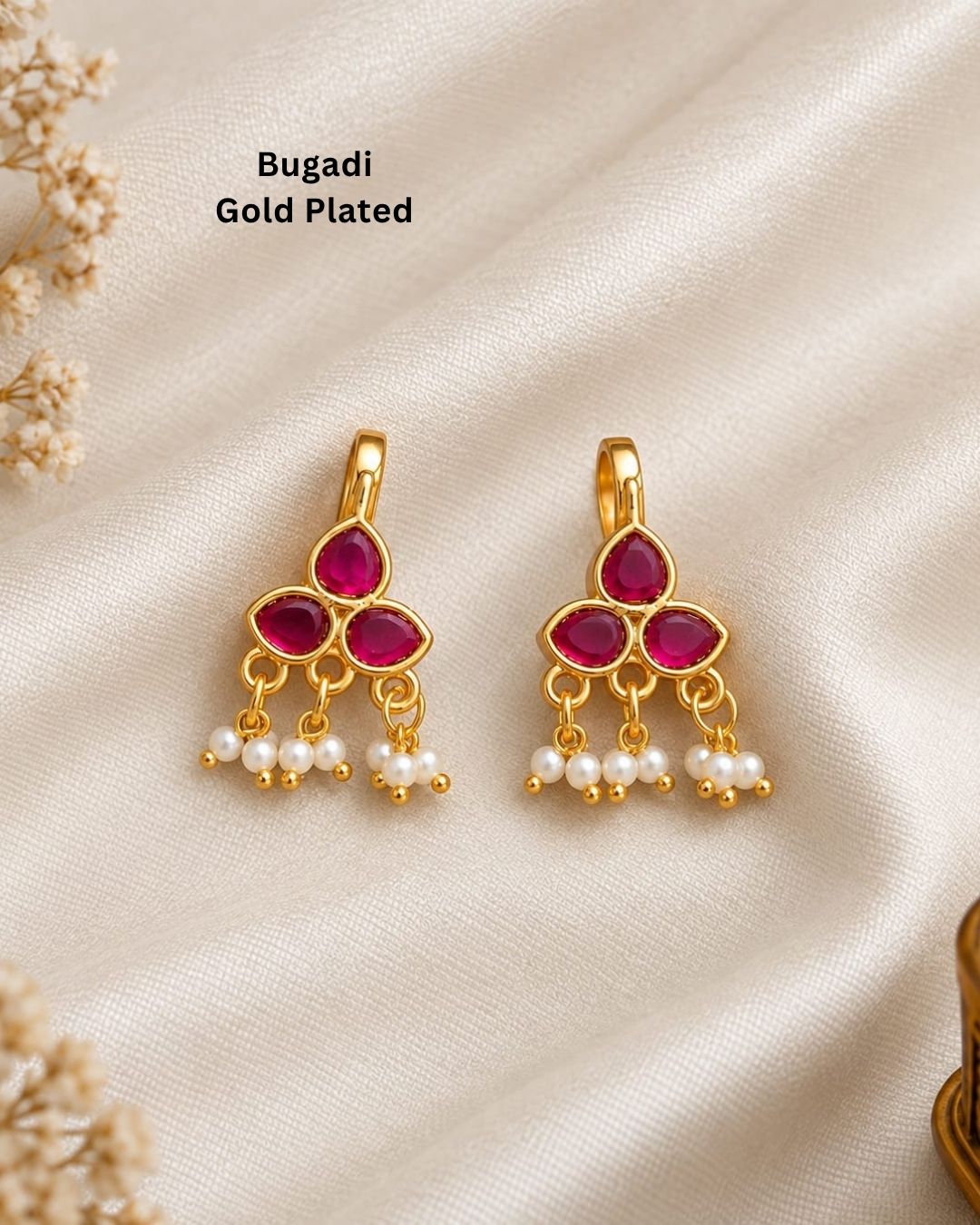 Premium gold plated bugadi earrings featuring a stylish three-stone floral design with rich ruby-colored stones and delicate hanging pearl clusters. Perfect for traditional wear, weddings, festive occasions, parties, and gifting.