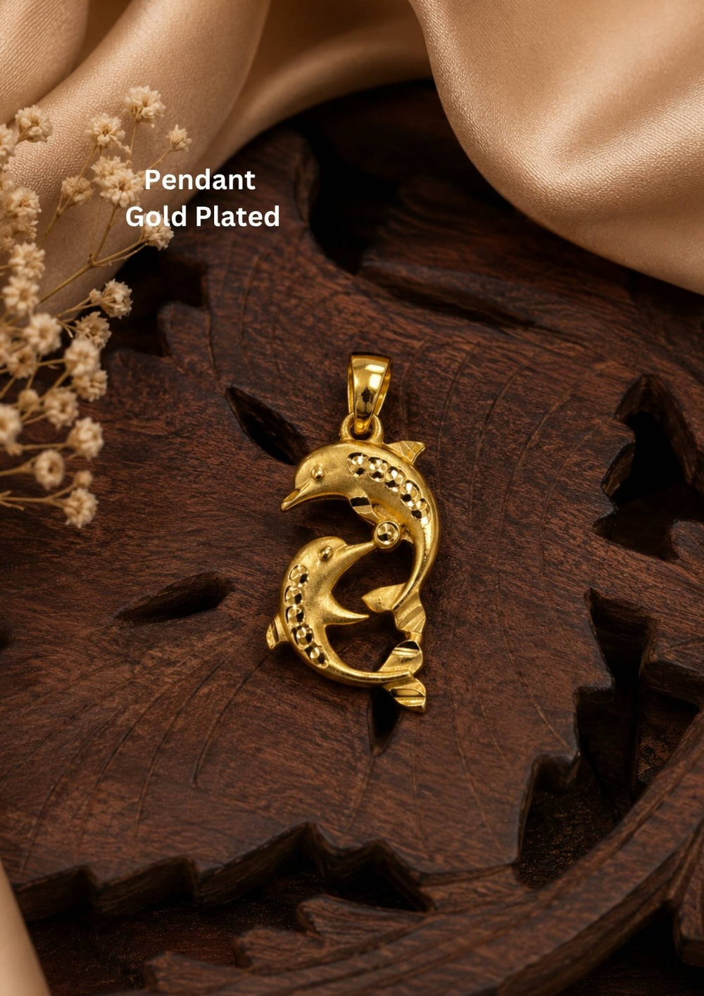 Gold-plated pendant necklace featuring a dolphin design with small clear stones, displayed on a dark wooden surface with beige satin fabric and dried flowers. Text overlay reads 'Gold Plated Pendant Set'.