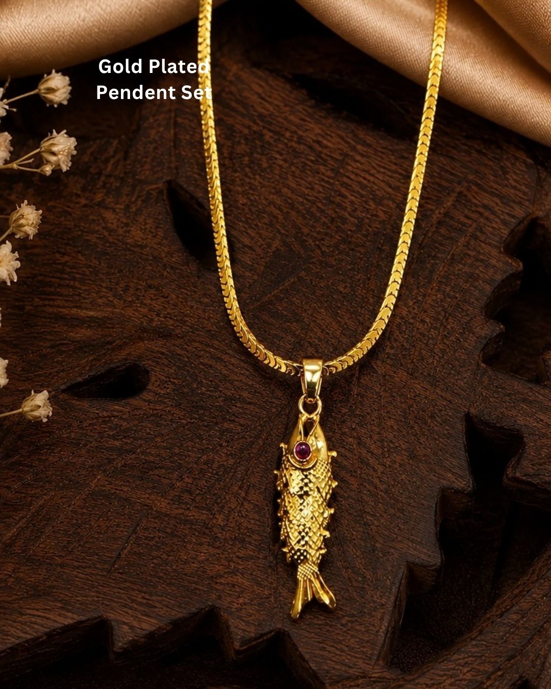 Traditional-inspired fish pendant with gold plated finish and matching chain, styled on a wooden background.