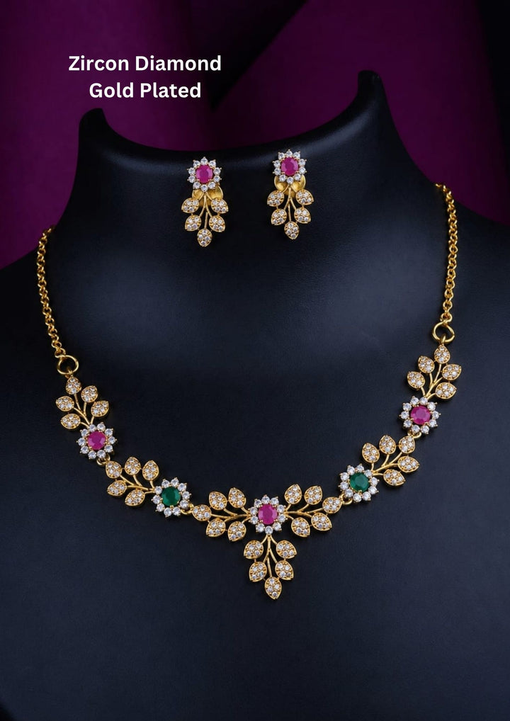 Elegant zircon diamond gold plated necklace set featuring sparkling leaf-shaped zircon motifs arranged in a graceful floral vine pattern. The necklace is highlighted with vibrant pink and green center stones surrounded by shimmering white zircon accents, creating a sophisticated and feminine look. The matching floral drop earrings complement the necklace beautifully, making it ideal for weddings, receptions, parties and festive occasions.