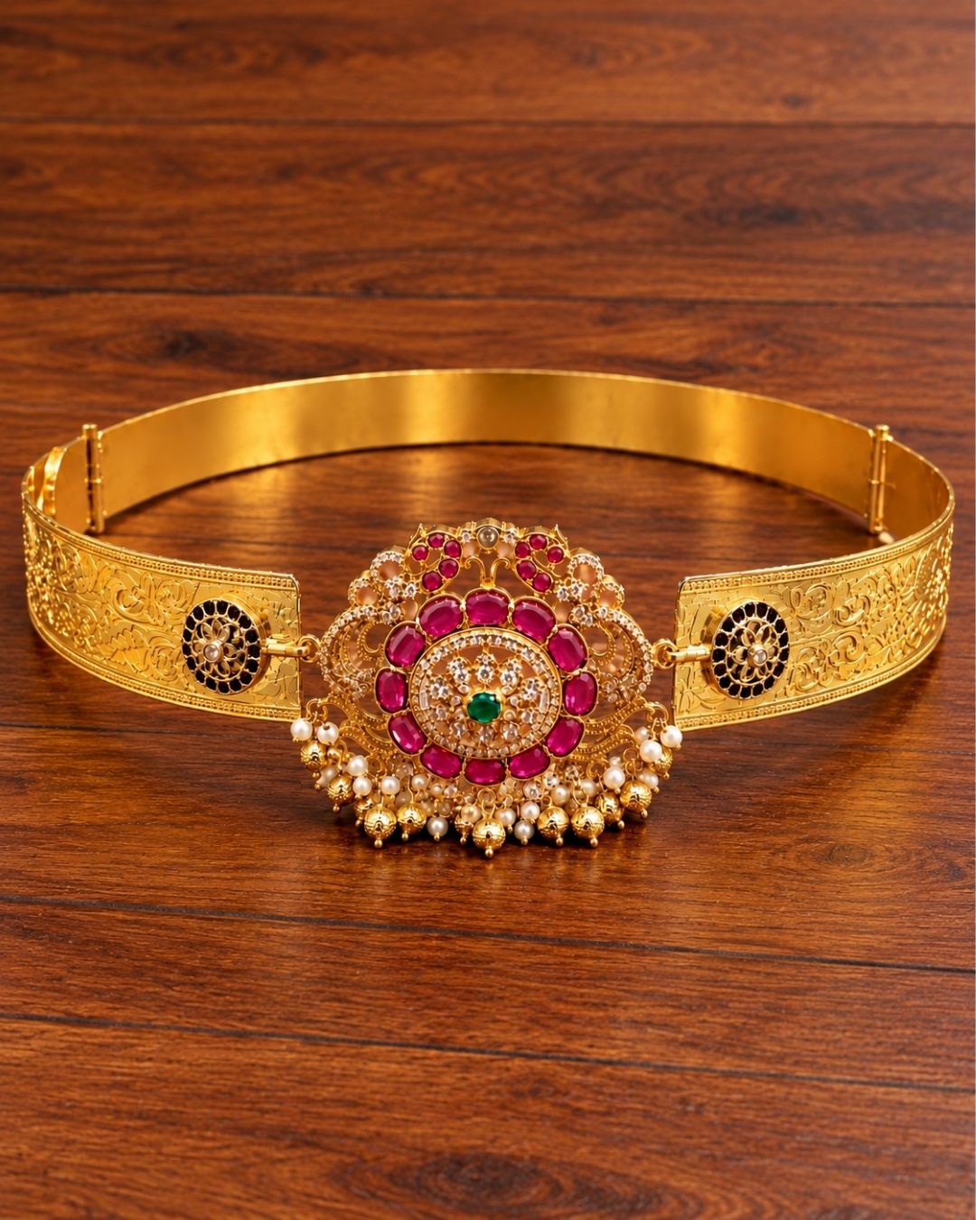 Traditional gold plated women’s hip belt with an intricately detailed floral centerpiece, colorful stones, sparkling accents, and pearl drops, perfect for festive and ethnic occasions.