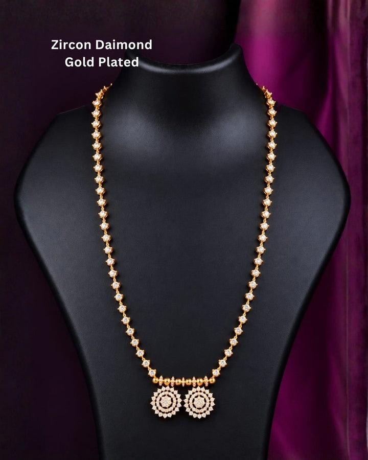 Gold plated designer mangalsutra arranged on a purple background, showcasing its delicate chain and twin round stone pendants.