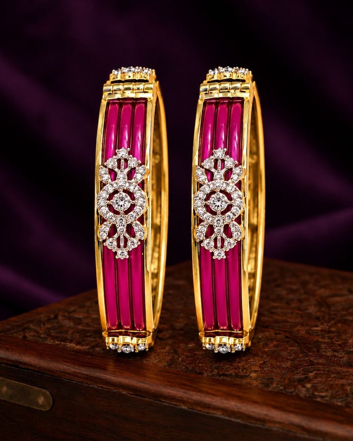 Designer gold plated bangles featuring deep blue detailing, sparkling white stone floral motifs, and polished gold borders, perfect for festive, wedding, traditional, and special occasions.