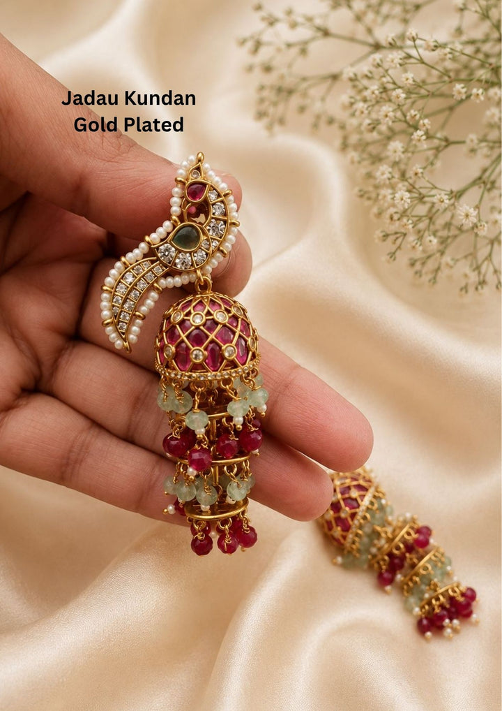Jadau kundan gold plated multi-tier jhumka earrings featuring a crescent moon stud element adorned with white pearls, clear kundan stones, and an emerald drop, leading down to a filigree dome cap packed with hanging tiers of ruby red and mint green quartz beads. This lightweight statement earring set provides a rich and classy appearance suitable for weddings, festivals, receptions with skin friendly quality, anti fade polish, comfortable fitting .
