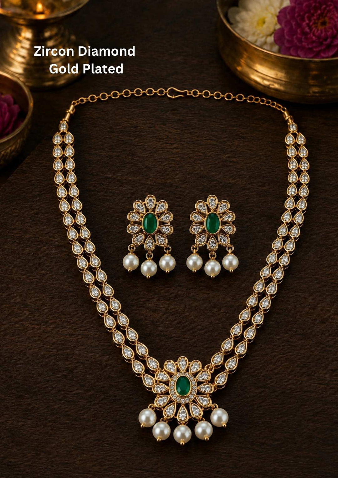 Zircon diamond gold plated two-layer necklace set featuring double rows of shimmering teardrop white zircon stones, an elegant central floral accent with an oval green emerald, and delicate hanging white pearls. This matching lightweight set includes floral emerald drop earrings with pearl details, providing a rich, royal appearance suitable for weddings, re-marriages, festivals, receptions, family functions, sarees, lehengas, and ethnic outfits with skin-friendly quality, anti-fade polish, comfortable fit.
