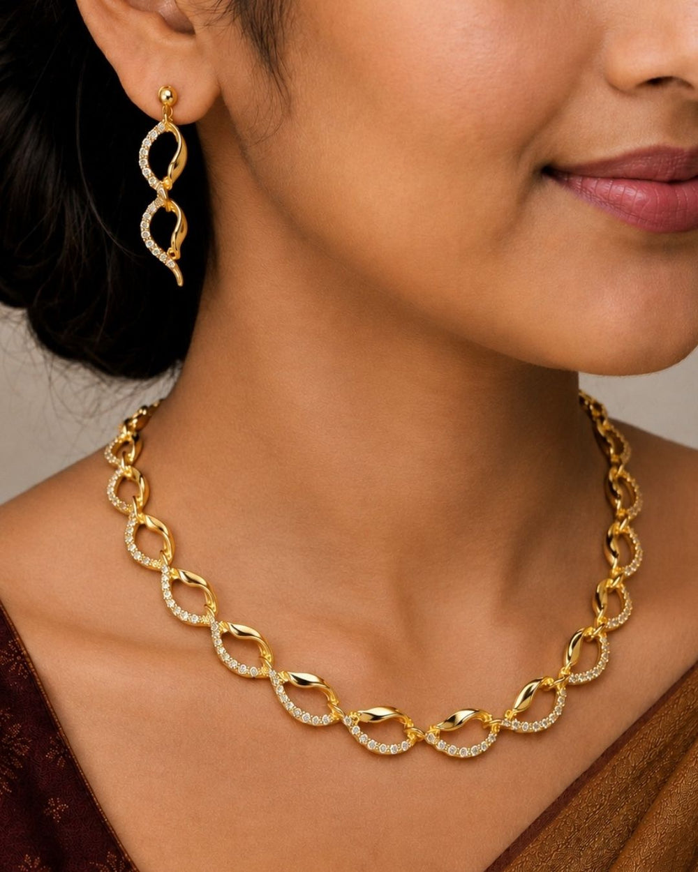 South Indian women Beautiful gold plated loop necklace set featuring interlinked curved motifs accented with sparkling clear stones and matching elegant drop earrings. Perfect for daily wear, festive occasions, parties, traditional outfits, and premium gifting.