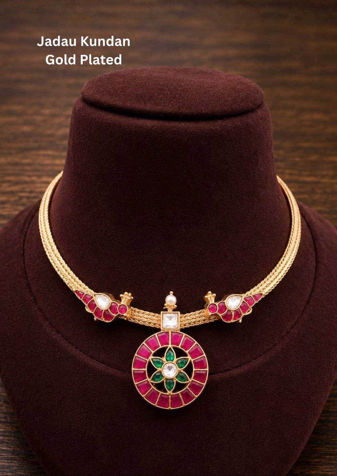 A beautifully sleek gold plated hasli choker necklace featuring a dual-strand twisted wire rigid collar band. The collar peaks on both sides with stylized pink enamel peacock motifs that hold a central geometric wheel pendant. The circular medallion is filled with rectangular hot pink crystals surrounding a green stone star flower centerpiece.
