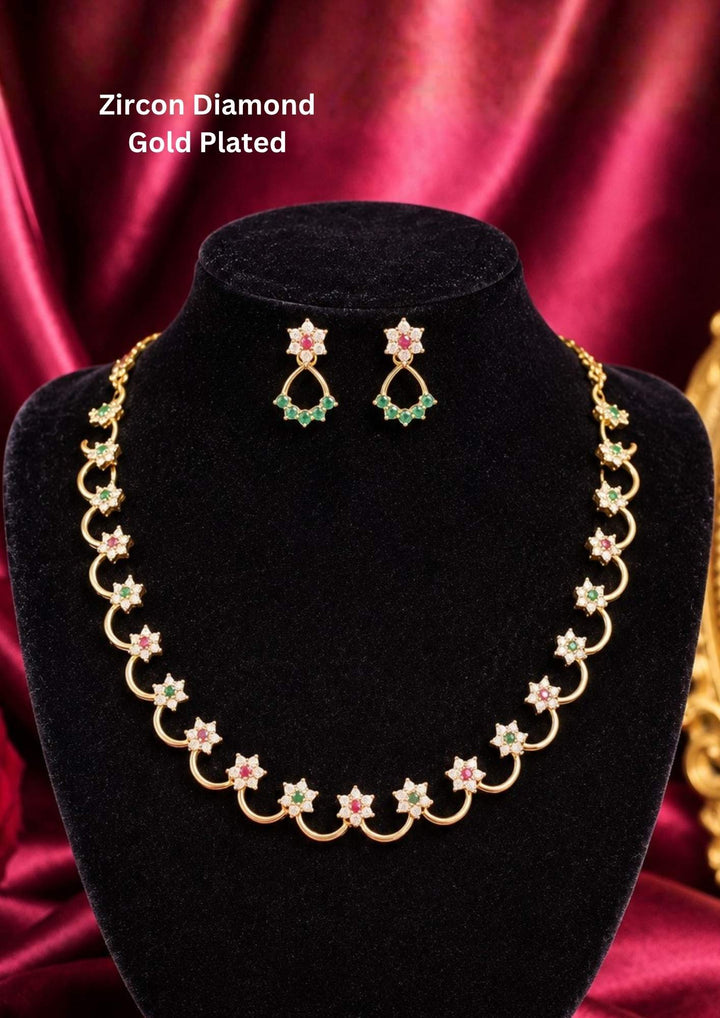 A delicate, lightweight 18k gold plated festive choker necklace featuring a continuous arrangement of scalloped open arch links. Each golden loop is centered with a shimmering clear zircon flower motif and alternating ruby-red and emerald-green stone centers, paired with matching dangling floral ear studs on a black presentation bust.