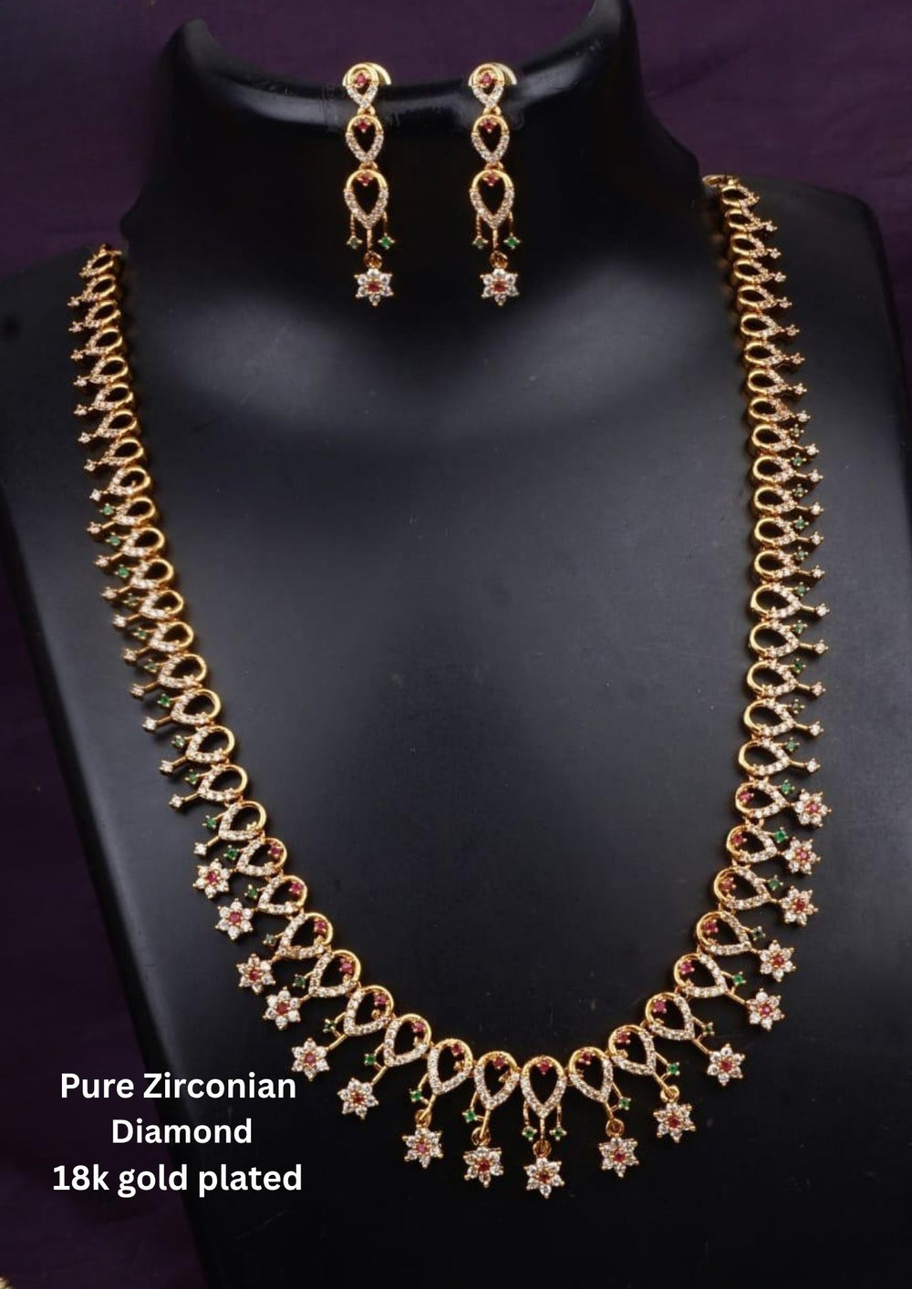 Traditional gold plated necklace set for women featuring ruby-red and emerald-green stones, sparkling accents, intricate teardrop patterns, and matching earrings, perfect for festive and ethnic wear.