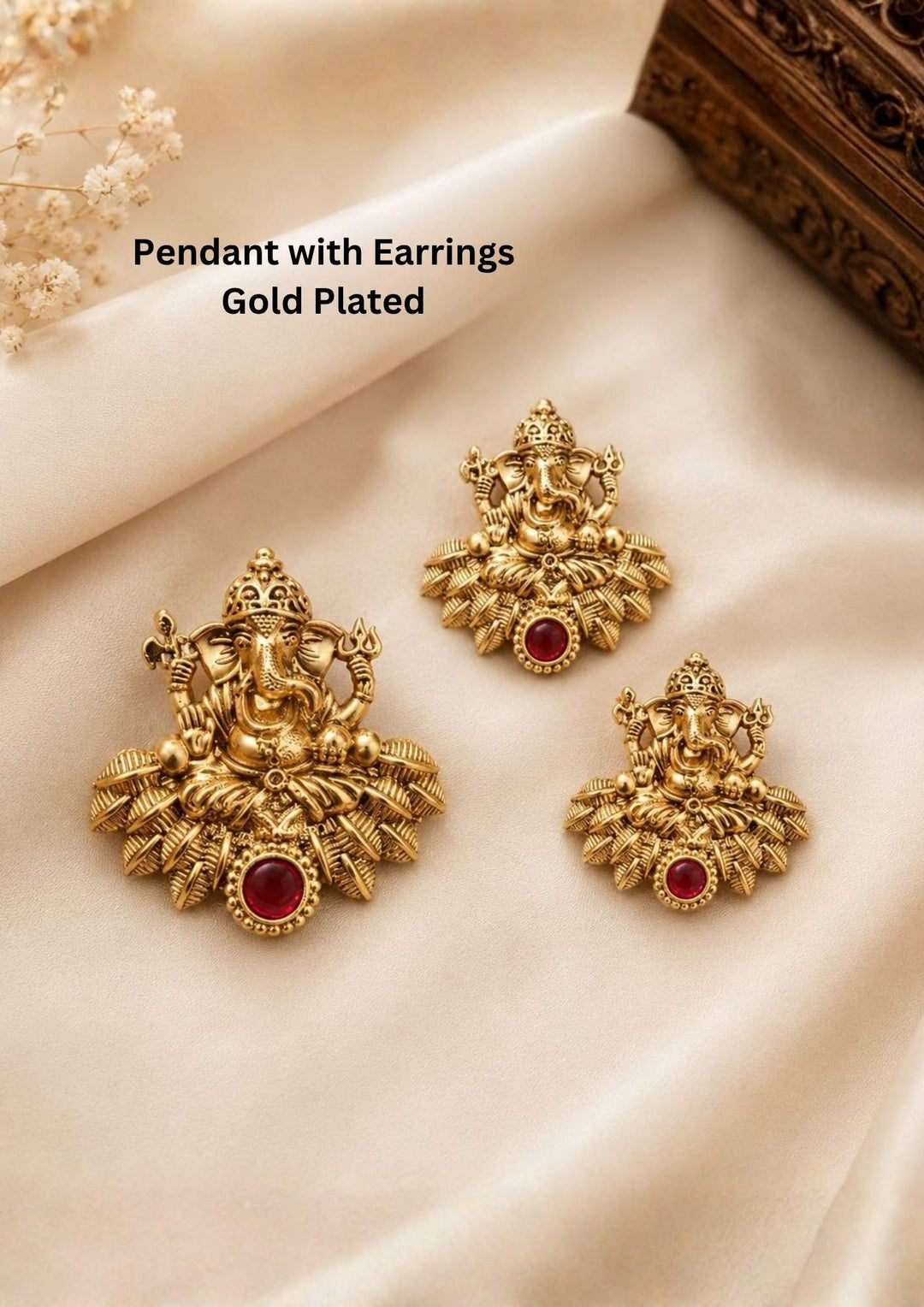 A divine antique gold plated temple jewelry set consisting of a medium-sized pendant and two matching smaller stud earrings. Each piece intricately depicts a multi-armed Lord Ganesha seated majestically upon a stylized bed of textured golden leaves. A smooth, round ruby-red stone is set right at the bottom center of each piece to complete the traditional design.