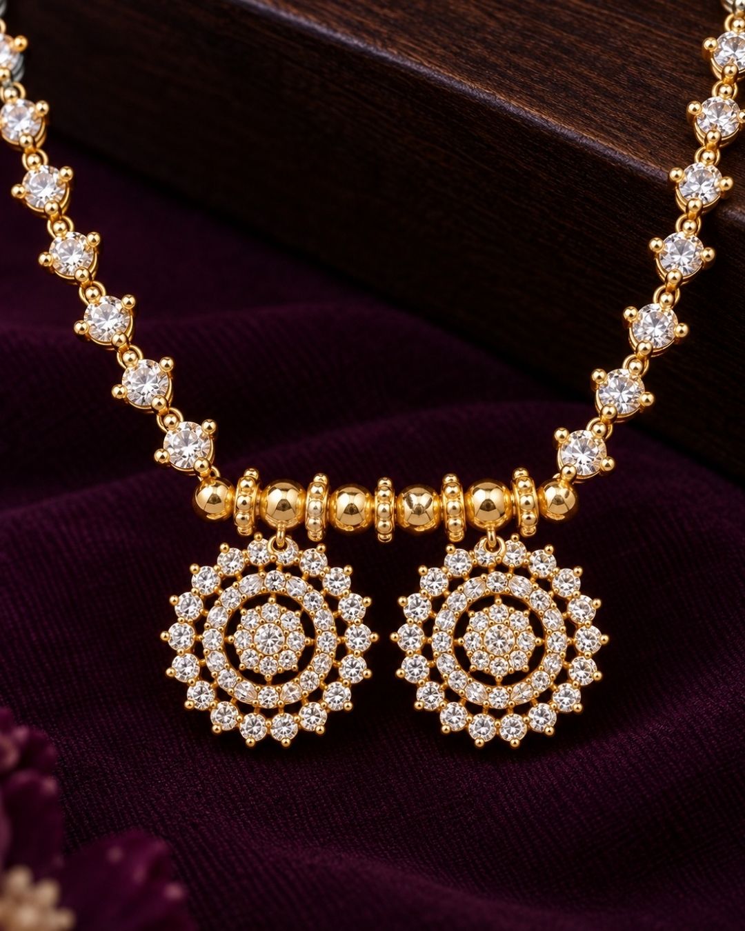 Gold plated designer mangalsutra arranged on a purple background, showcasing its delicate chain and twin round stone pendants.