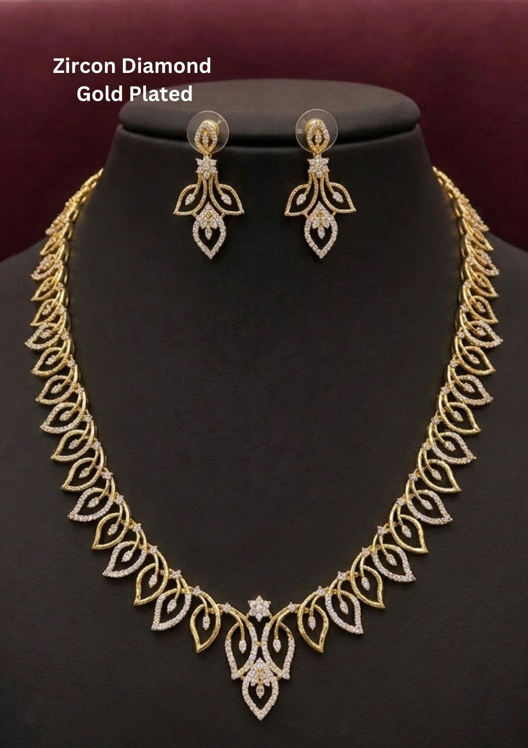 Elegant zircon diamond gold plated necklace set featuring a detailed leaf inspired pattern with sparkling white zircon stones arranged throughout the chain and center pendant. The matching designer earrings have a floral leaf drop design with shimmering diamond look stones, creating a graceful modern ethnic style suitable for weddings, receptions, parties and festive occasions.