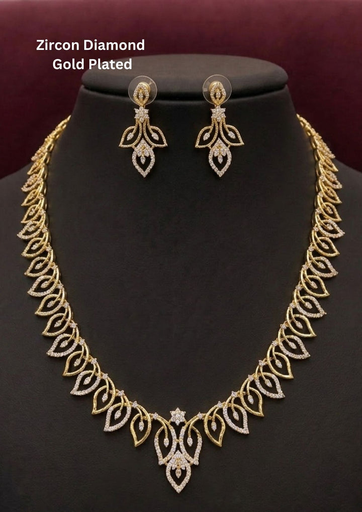 Elegant zircon diamond gold plated necklace set featuring a detailed leaf inspired pattern with sparkling white zircon stones arranged throughout the chain and center pendant. The matching designer earrings have a floral leaf drop design with shimmering diamond look stones, creating a graceful modern ethnic style suitable for weddings, receptions, parties and festive occasions.