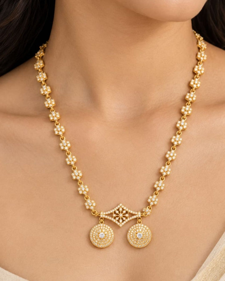 Elegant gold plated necklace with sparkling white stones, floral motifs, and two round dangling pendants.
