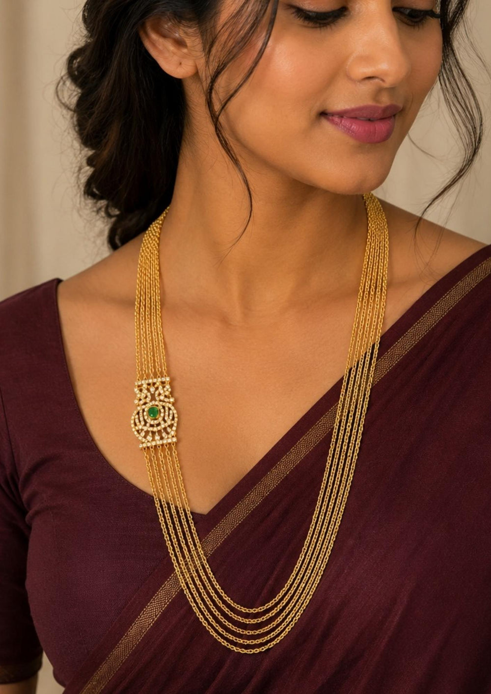 Close up of a south indian women wearing Elegant multi layer Chandraharam gold plated haram featuring fine layered chains with a beautifully crafted zircon centerpiece accented by a green stone. Perfect for weddings and festive occasions.