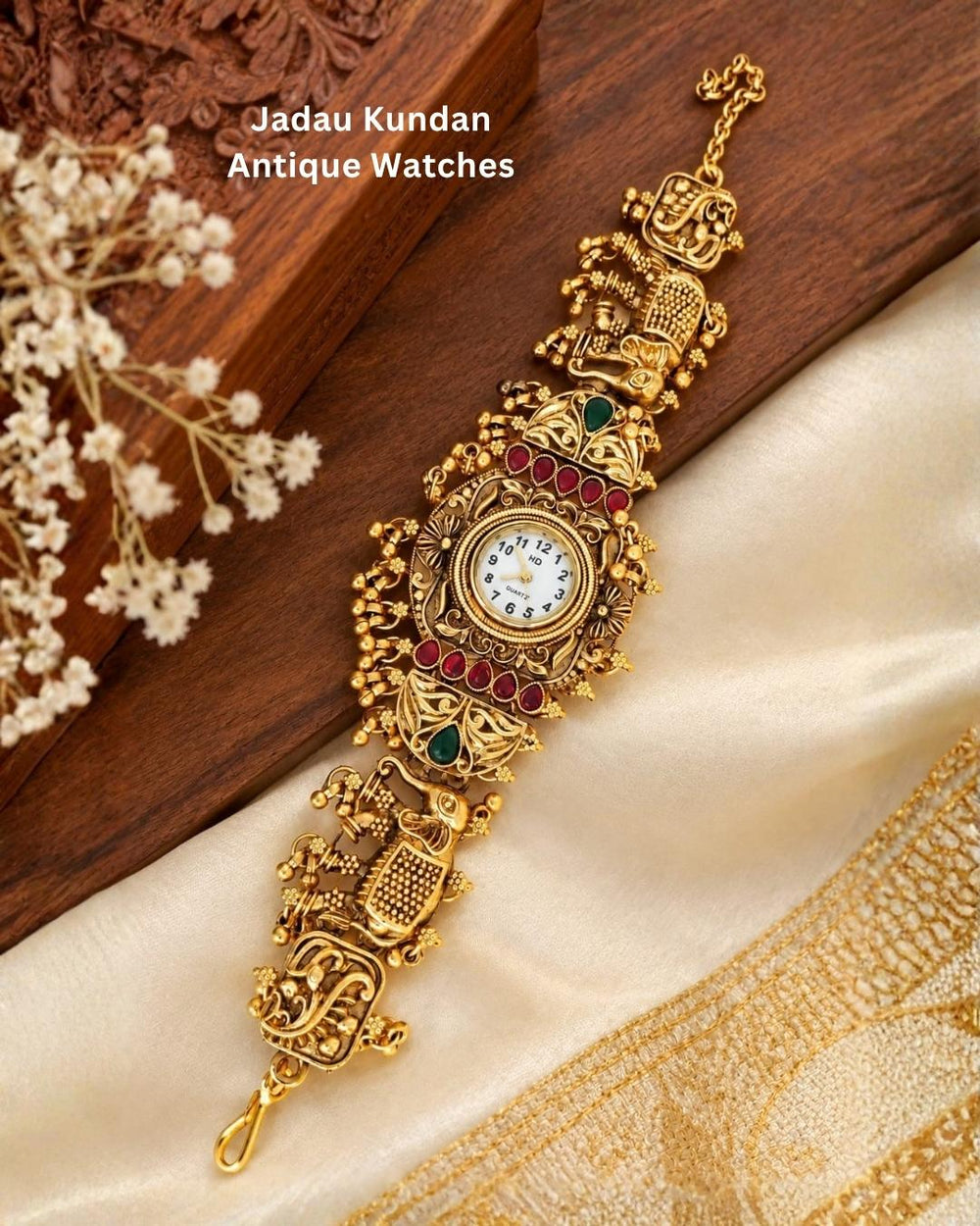 Antique gold plated bracelet watch displayed diagonally on cream fabric and a wooden surface with delicate floral accents.