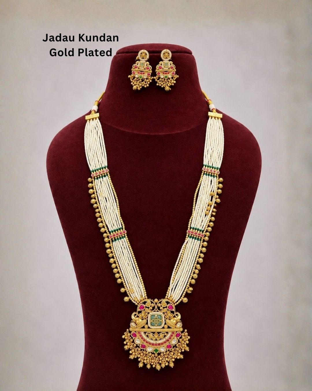 Traditional gold plated necklace set with layered white bead strands, green and pink stone accents, an elaborate pendant with dangling beads, and matching earrings, perfect for festive and ethnic occasions.