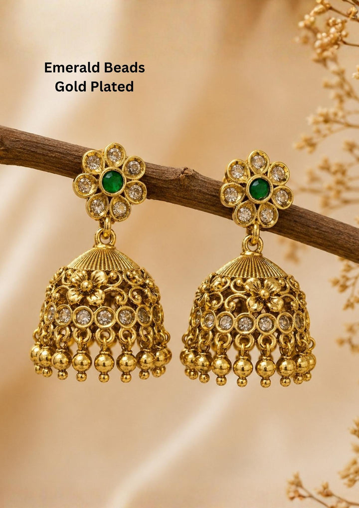 Elegant emerald beads gold plated jhumka earrings featuring floral stud tops adorned with sparkling white stones and green center beads. The dome-shaped jhumkas showcase intricate antique detailing with hanging gold bead danglers, creating a timeless traditional look.