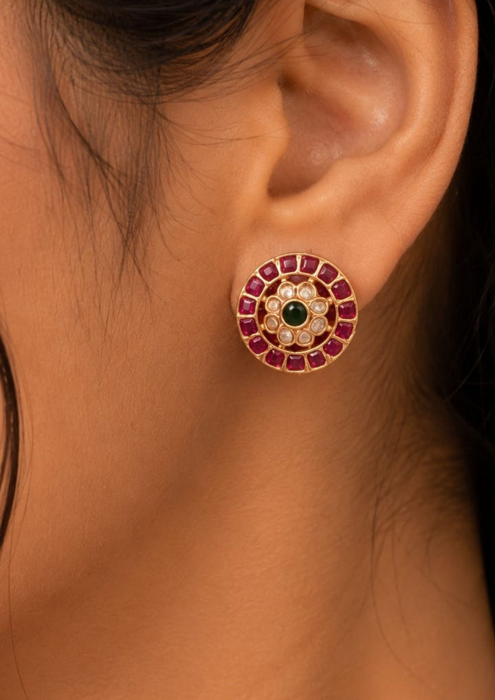 south Indian women wearing a kante necklace set with studs . Detailed view of the circular Kemp stone stud earrings and the matching Kante necklace pendant. The jewelry showcases premium antique gold plating, precise square-cut red stones, and central green accents, offering a sweat-proof, anti-fade, and high-quality traditional look for festive celebrations.