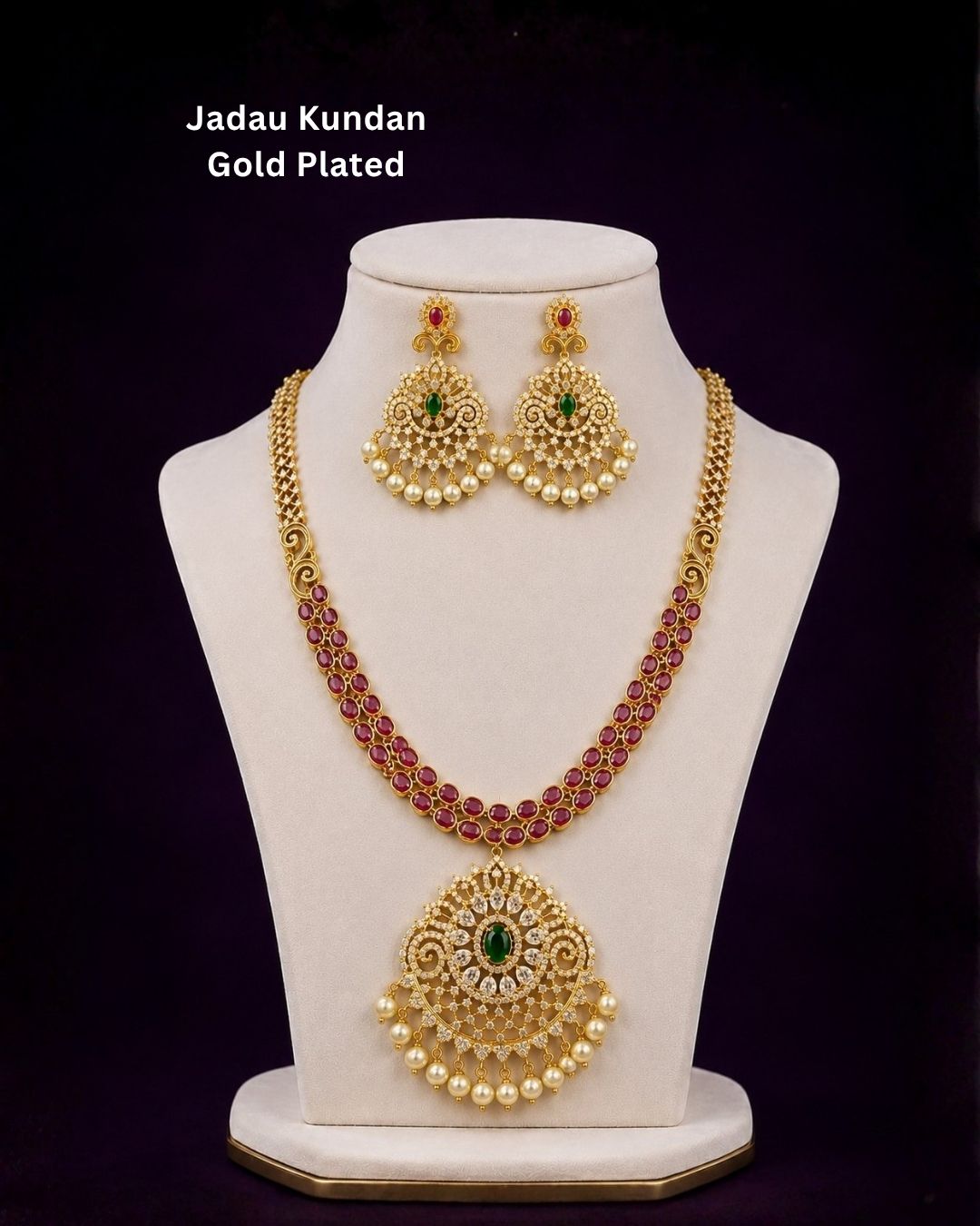 Premium gold plated CZ jewelry set with a ruby stone necklace, floral pendant, emerald green accents, pearl embellishments, and matching earrings for weddings and parties.