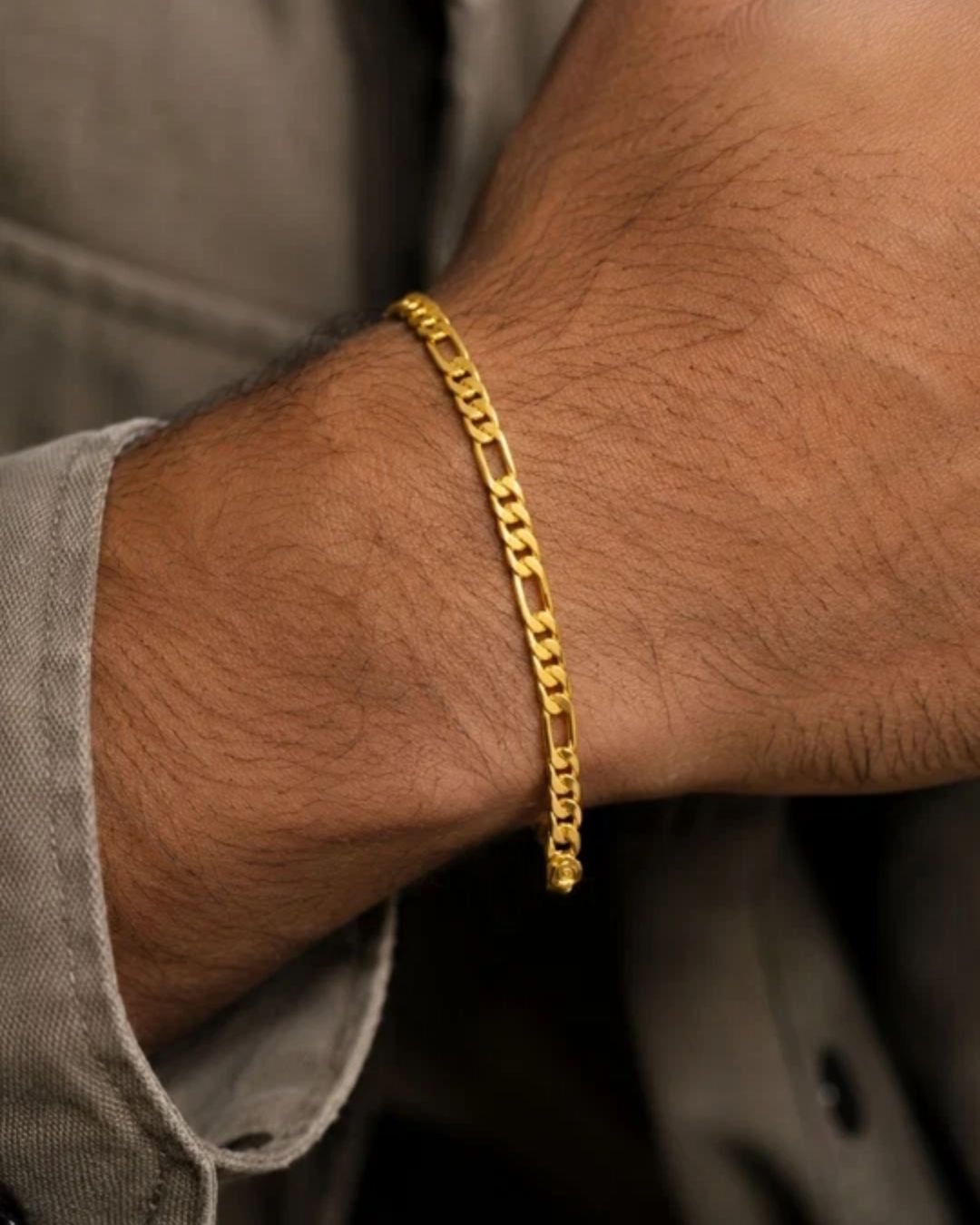 Close up of south indian men wrist wearing An elegant, sleek 18k gold-plated bracelet  features a continuous, sophisticated pattern of repeating cylindrical bar links seamlessly interconnected with small circular loops, offering a clean and polished modern look. Perfect for daily wear or for pairing with your favorite pendant.
