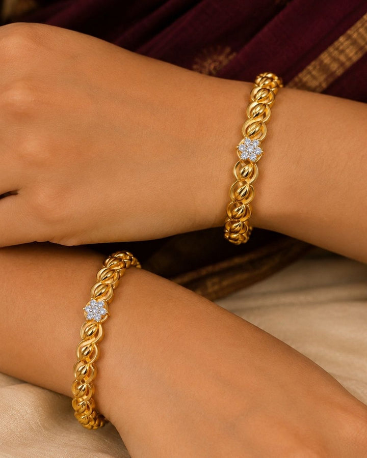 Beautiful gold plated bangles featuring a repeating twisted leaf pattern with floral stone accents at the center. Perfect for traditional wear, festive occasions, weddings, daily wear, and gifting.