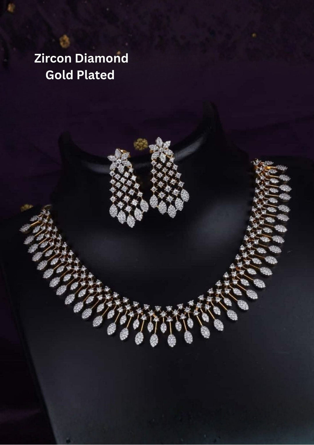 Elegant zircon diamond gold plated necklace set featuring a graceful collar-style necklace adorned with sparkling white zircon stones and cascading leaf-shaped dangling motifs. The matching statement earrings showcase a floral-inspired top with intricate stone-studded lattice detailing and shimmering leaf drops, creating a luxurious and sophisticated look suitable for weddings, receptions, parties and festive occasions.