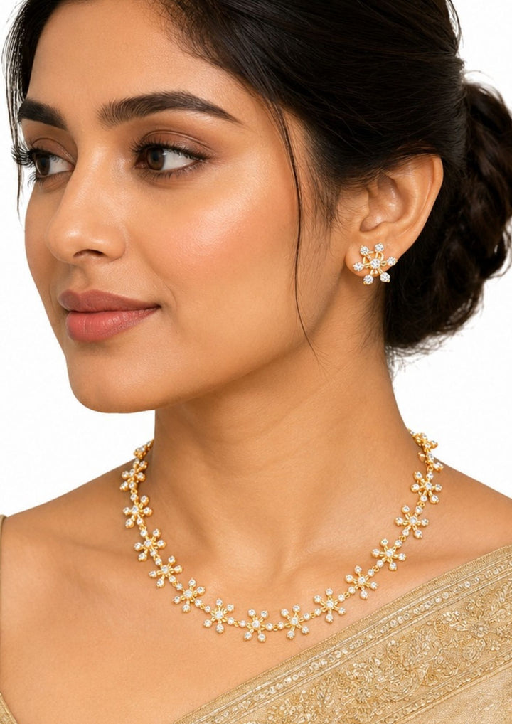 Modern Indian woman wearing Gold Plated Floral Necklace Set with floral zircon stone detailing and matching earrings that gives a modern elegant jewelry look. The necklace set shows sparkling stone with lightweight comfort, sweat proof finish, anti-fade colour, and is suitable for parties, festivals, functions, and wedding occasions.