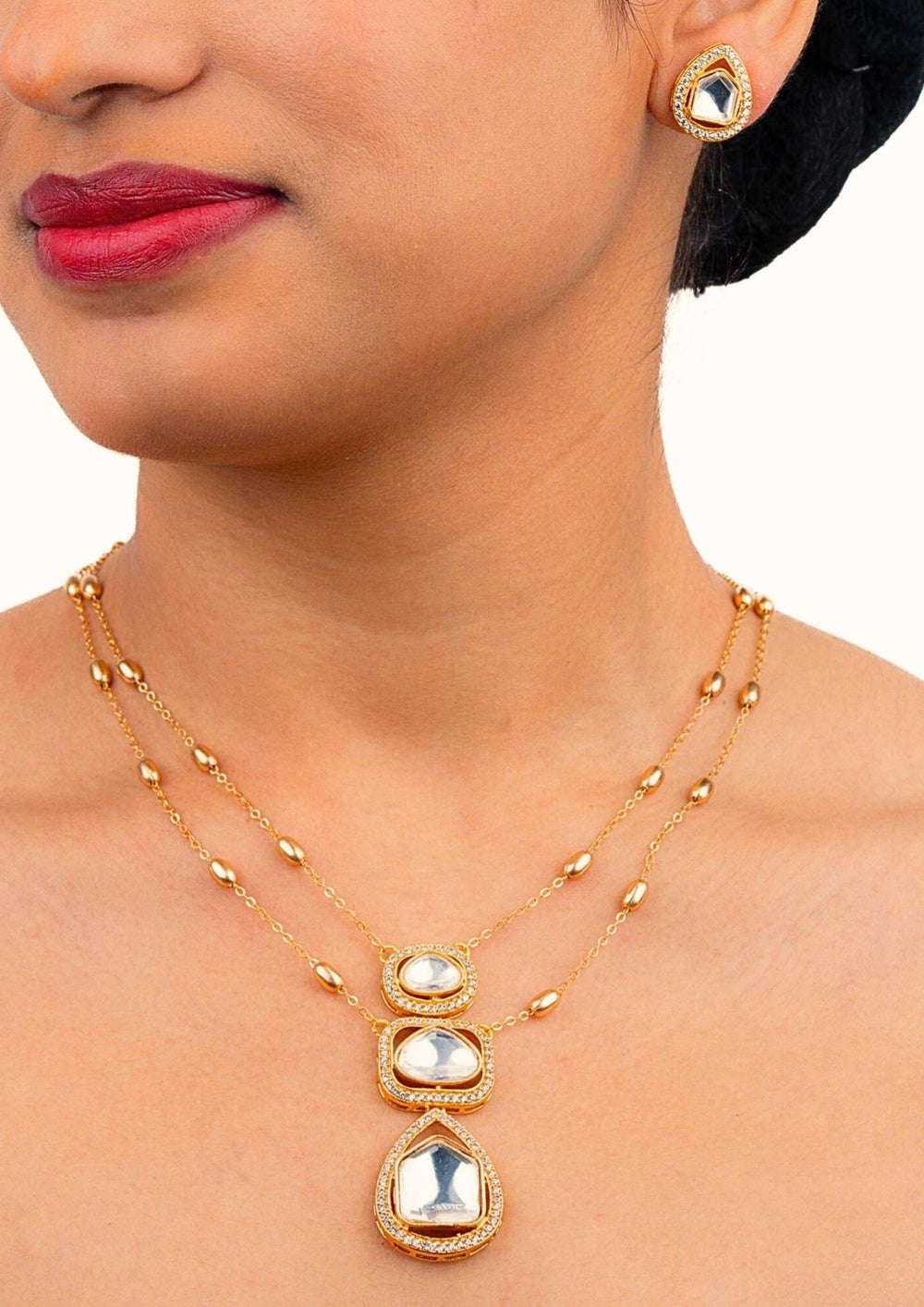 Close-up of a woman wearing a gold necklace with a pendant and matching earrings