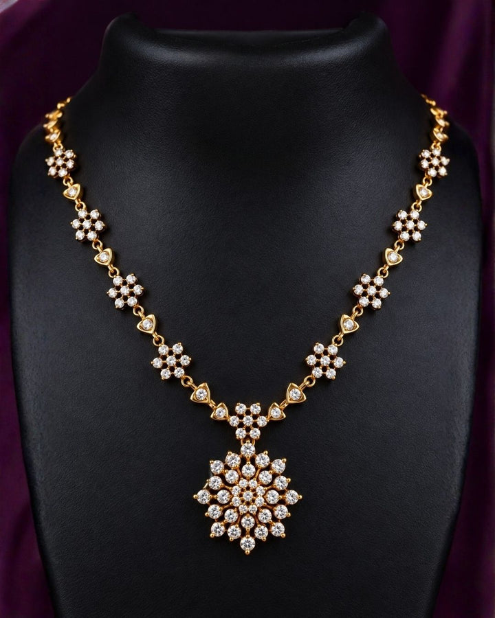 Zircon diamond gold-plated necklace set showcasing an intricate chain linked with tiny floral stone clusters and a beautiful geometric snowflake statement pendant. The matching earrings perfectly mirror the pendant&