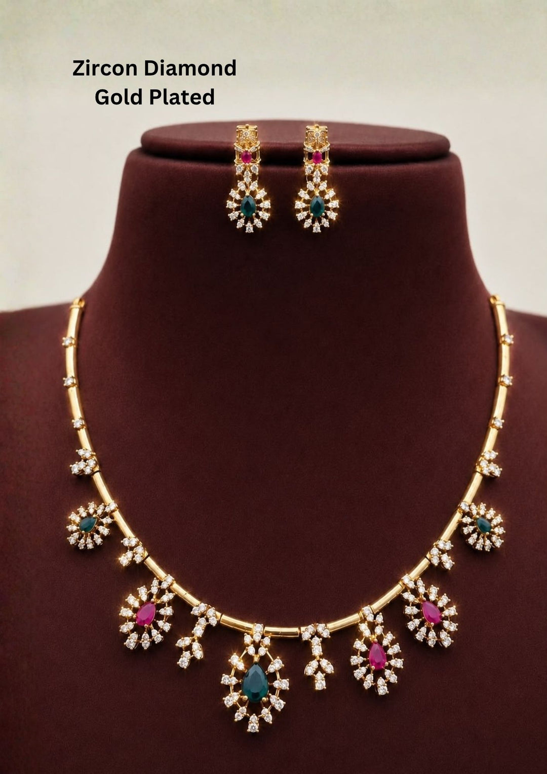 Gold-plated necklace and matching drop earrings features gold-tone settings with clear stones, turquoise blue teardrop stones, and pink round stones. Premium gold plated necklace set crafted with sparkling zircon stones, floral charms, and matching earrings for festive and party wear.