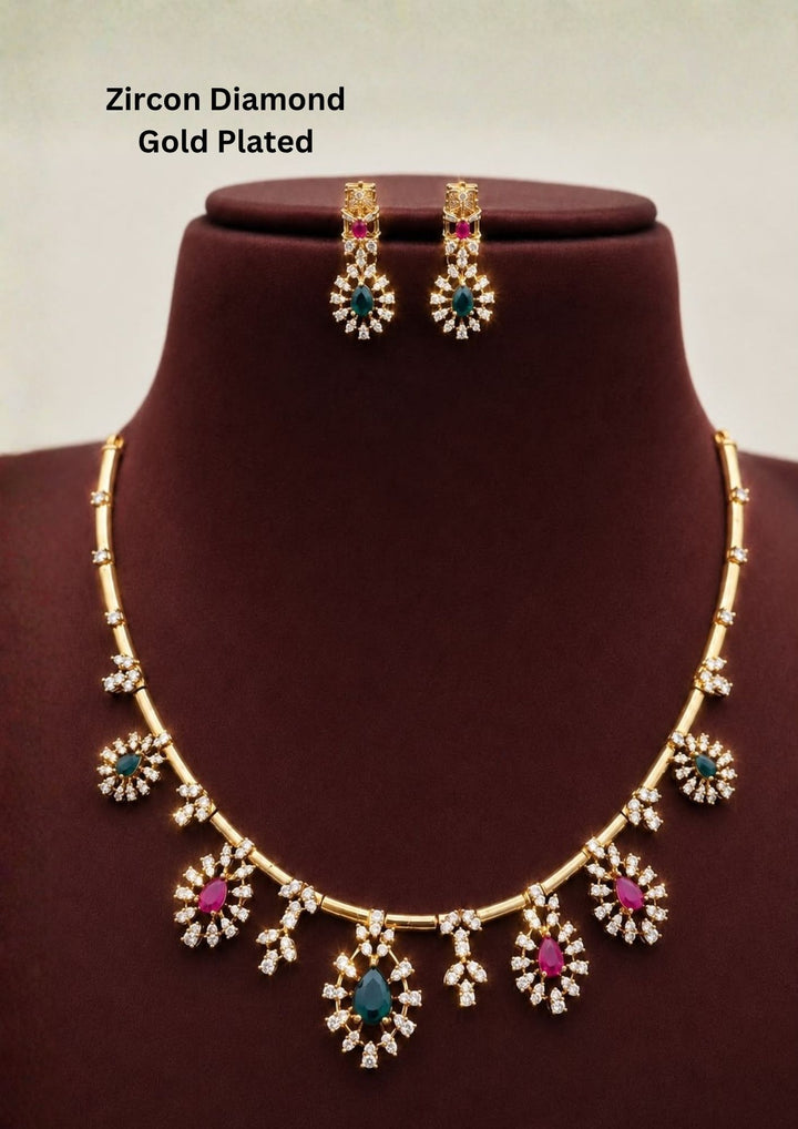 Gold-plated necklace and matching drop earrings features gold-tone settings with clear stones, turquoise blue teardrop stones, and pink round stones. Premium gold plated necklace set crafted with sparkling zircon stones, floral charms, and matching earrings for festive and party wear.