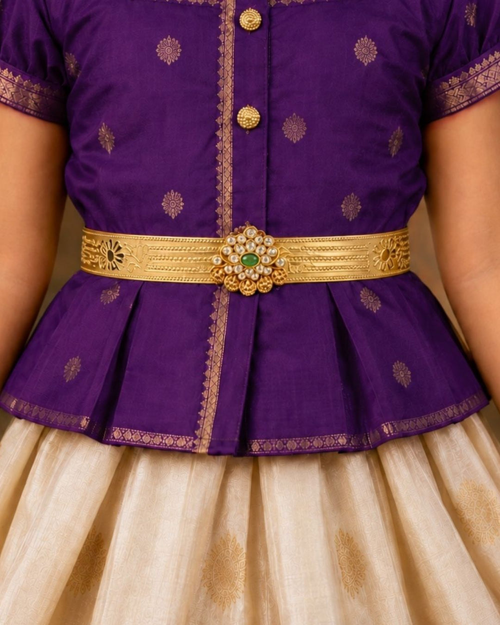 Beautiful gold plated kids hip belt featuring an intricately engraved wide band with floral motifs and a central green gemstone surrounded by sparkling clear stones. Perfect for traditional wear, weddings, festive occasions, cultural celebrations, and gifting.