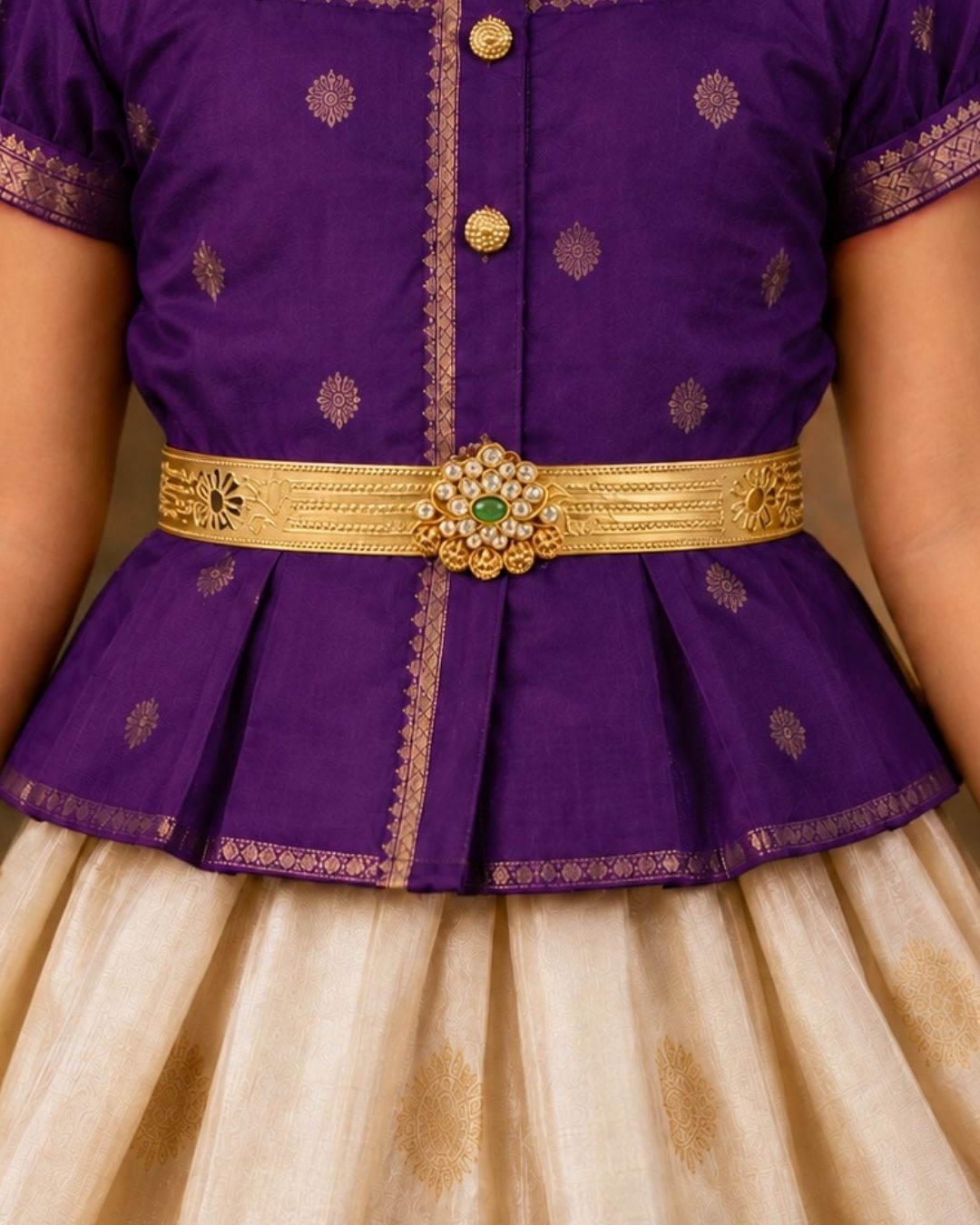 Beautiful gold plated kids hip belt featuring an intricately engraved wide band with floral motifs and a central green gemstone surrounded by sparkling clear stones. Perfect for traditional wear, weddings, festive occasions, cultural celebrations, and gifting.