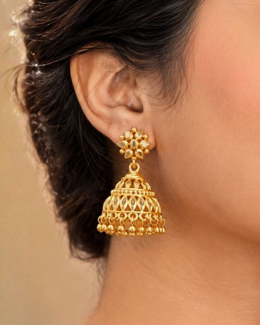 Premium gold plated traditional jhumka earrings featuring intricate floral craftsmanship, detailed dome-shaped designs, and elegant hanging gold bead accents. Perfect for sarees, festive occasions, weddings, classical dance performances, and traditional events.