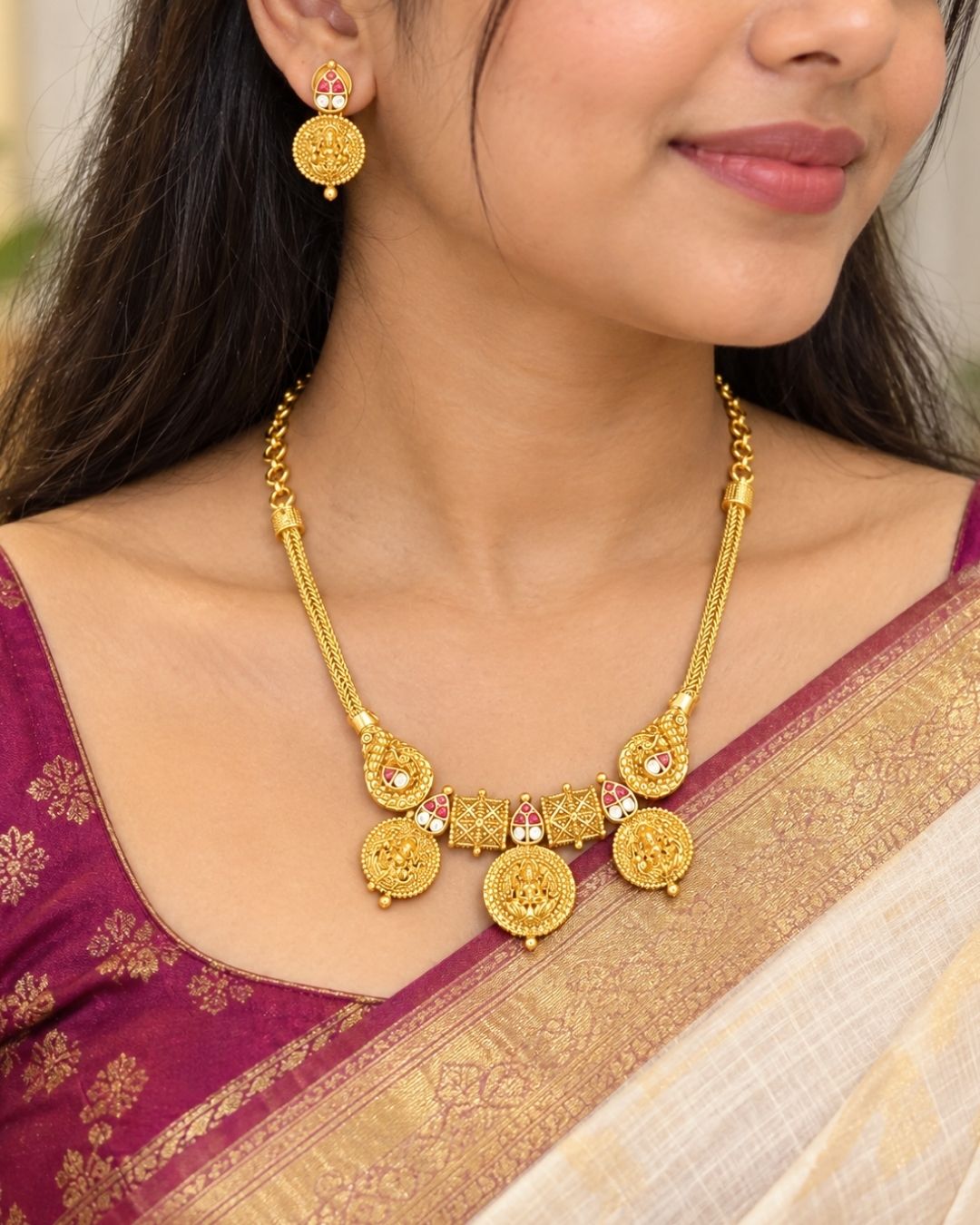 Traditional gold plated designer necklace and earrings set featuring multiple Goddess Lakshmi coin motifs, intricate temple-inspired detailing, ruby-colored stone accents, and matching decorative earrings, perfect for festive, wedding, and traditional occasions.