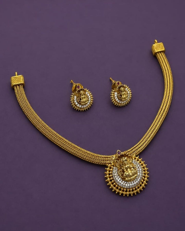 Beautiful Lakshmi gold plated necklace set featuring an intricate Goddess Lakshmi pendant surrounded by white stone detailing and traditional bead accents, paired with matching earrings. Perfect for festive occasions, weddings, temple visits, traditional outfits, and gifting.