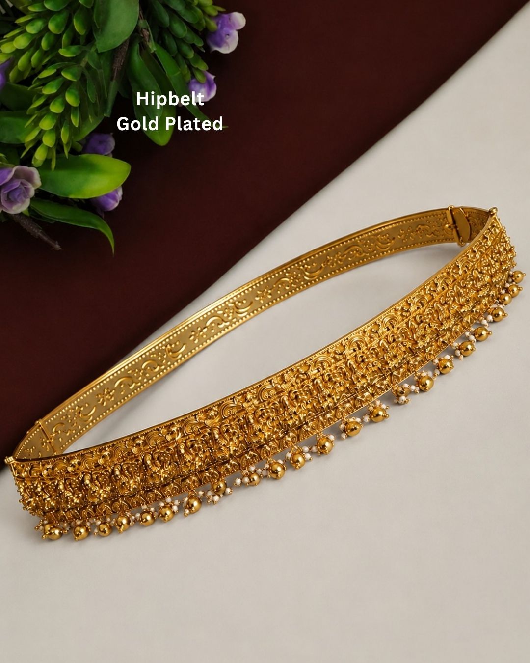 Beautiful traditional gold plated hip belt featuring intricate temple-inspired craftsmanship and dangling gold and pearl accents. Perfect for sarees, weddings, festive occasions, classical dance performances, and traditional events.