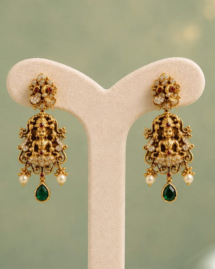Premium antique gold plated temple necklace and earrings set crafted with intricate Ganesha and peacock designs, sparkling CZ stones, green accents, and elegant pearl details.