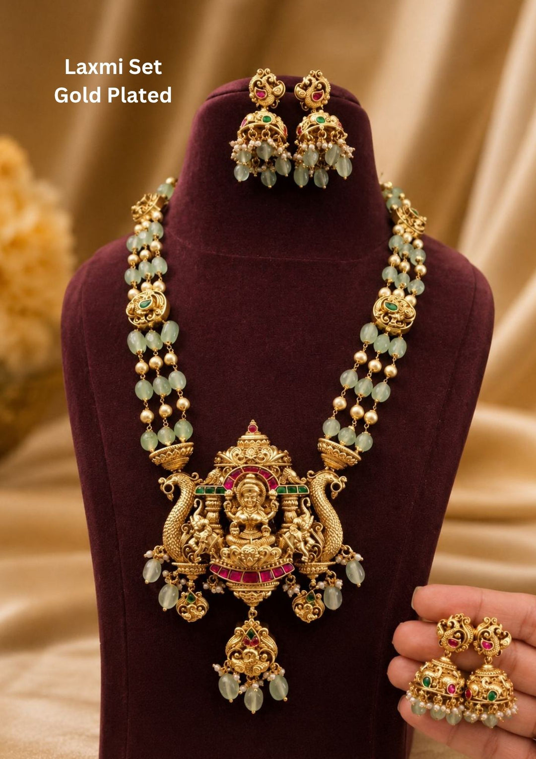 Jadau Kundan Gold Plated Laxmi Temple necklace set with matching jhumka earrings designed with three  rows of pastel green beads and gold pearls with gold pendant with Goddess Laxmi, peacocks, ruby red stones, and hanging bead drops. perfect for weddings, festivals, receptions, and cultural South Indian jewellery styling.