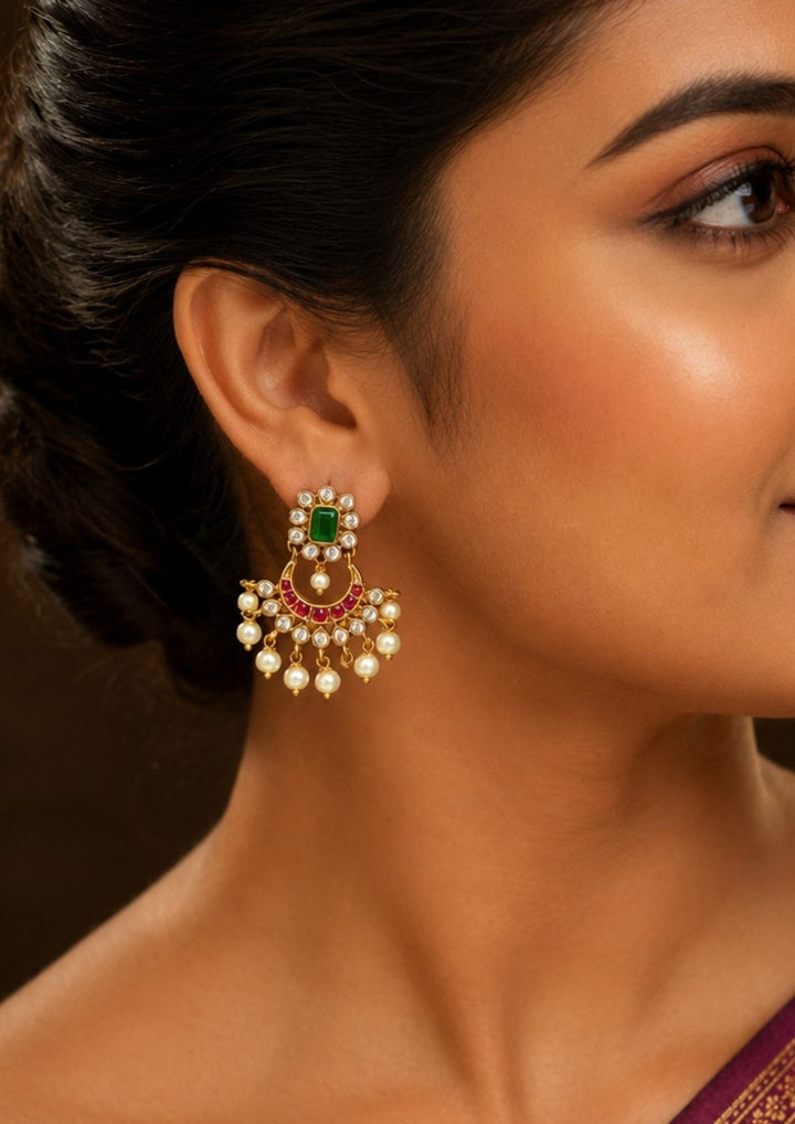 Close-up of a south indian woman wearing a Gold-plated earrings with green and red stones with Peral drops chandbali earrings with jadau kundan and shown clearly how it looks can be used for festivals and weeding&