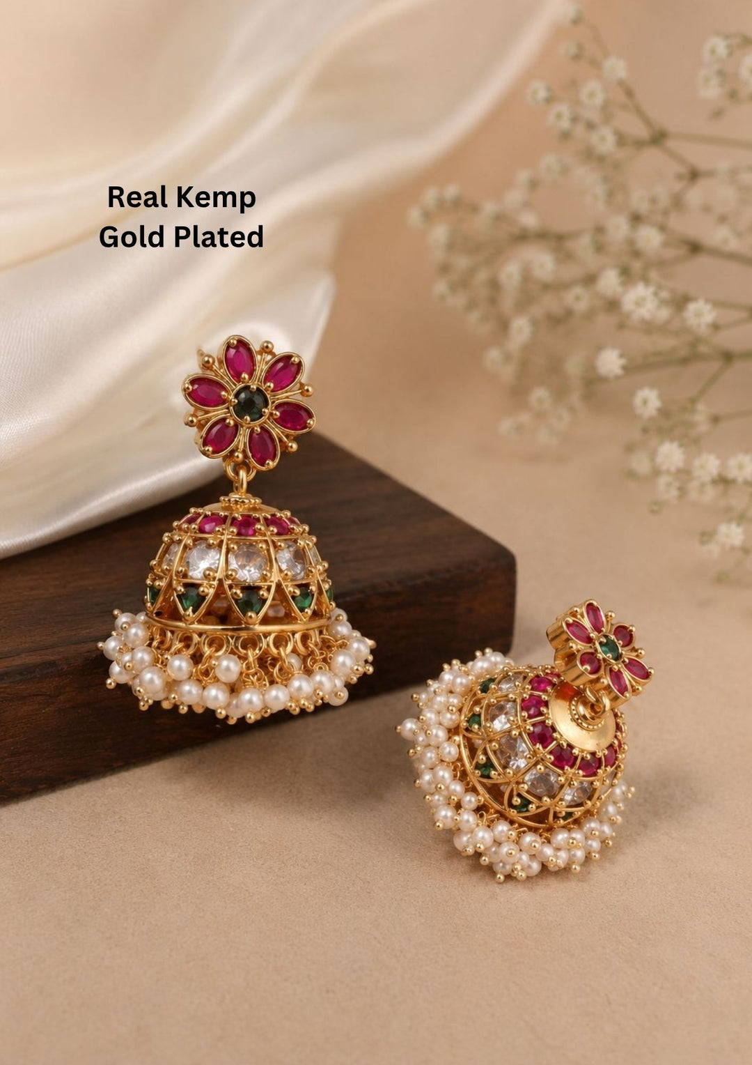 Gold-plated earrings with gemstones and pearls on a beige surface with flowers. perfect for weddings, poojas, festivals it is anti color fade and skin friendly
