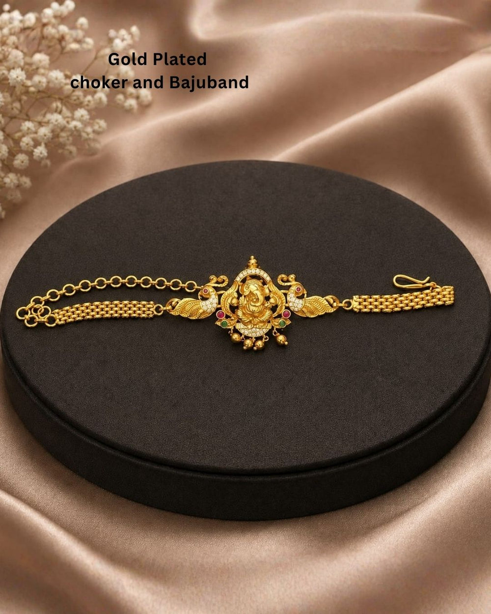 Premium gold plated choker and bajuband featuring an intricately crafted Goddess Lakshmi centerpiece surrounded by peacock motifs, white stones, red and green stone embellishments and delicate hanging gold beads. Perfect for weddings, festive occasions, traditional wear, dance performances, parties and gifting.
