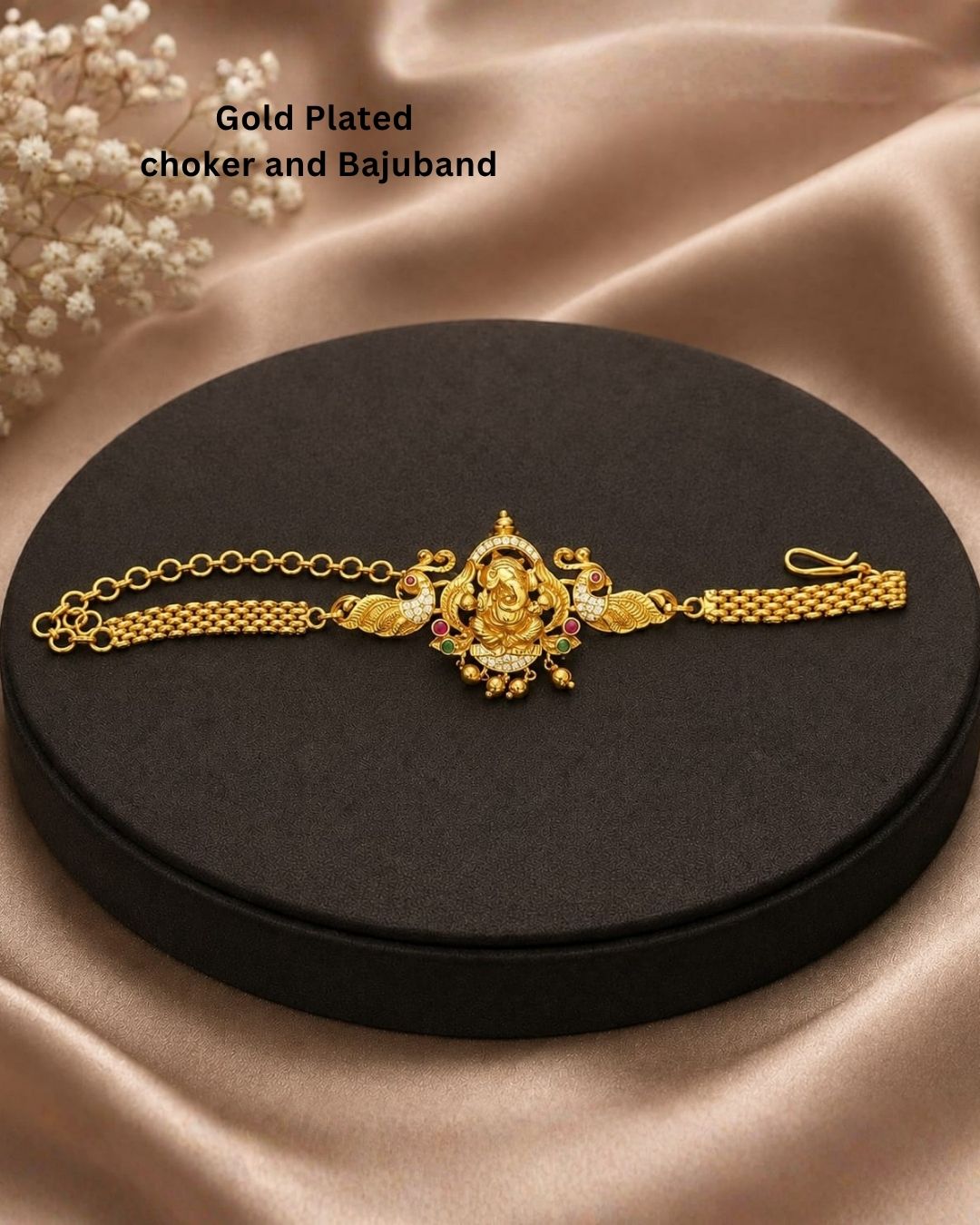 Premium gold plated choker and bajuband featuring an intricately crafted Goddess Lakshmi centerpiece surrounded by peacock motifs, white stones, red and green stone embellishments and delicate hanging gold beads. Perfect for weddings, festive occasions, traditional wear, dance performances, parties and gifting.